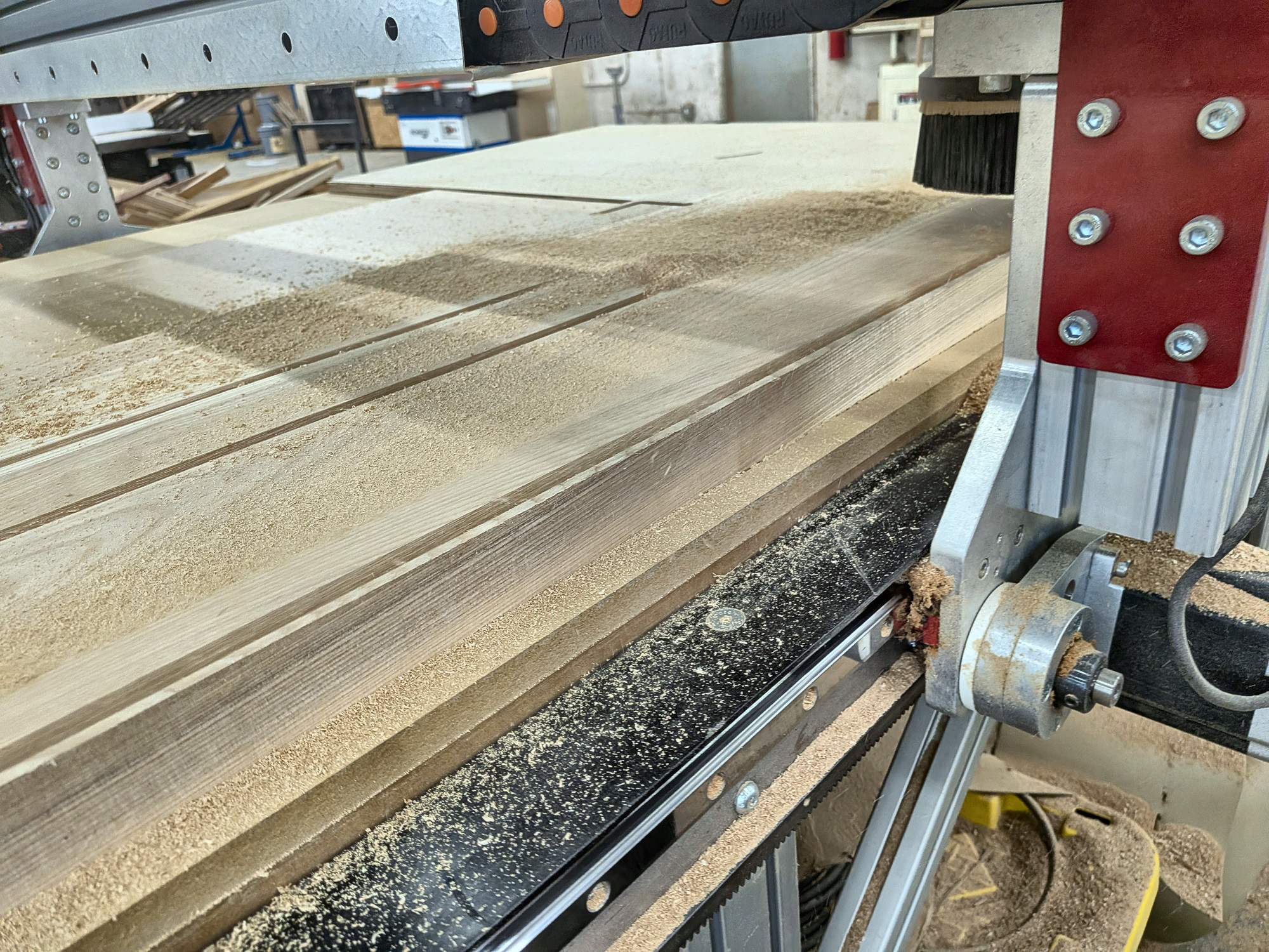 CNC router bit cutting the arched leg profile out of a glued-up ash panel