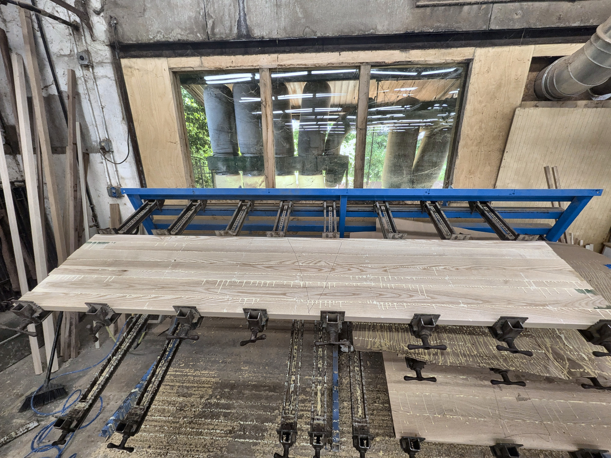 Ash boards clamped together on the bench, forming the table's top slab
